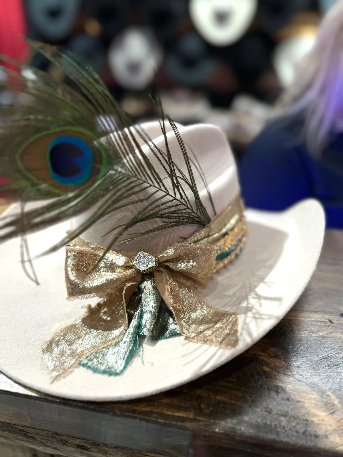 Custom hat decorated with a peacock feather, ribbons and a jeweled accent